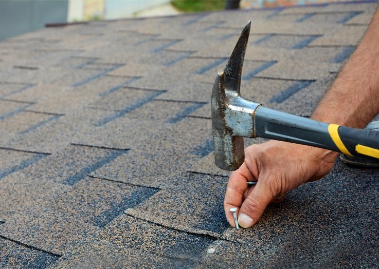 Roof repair contractor fixing shingles on roof