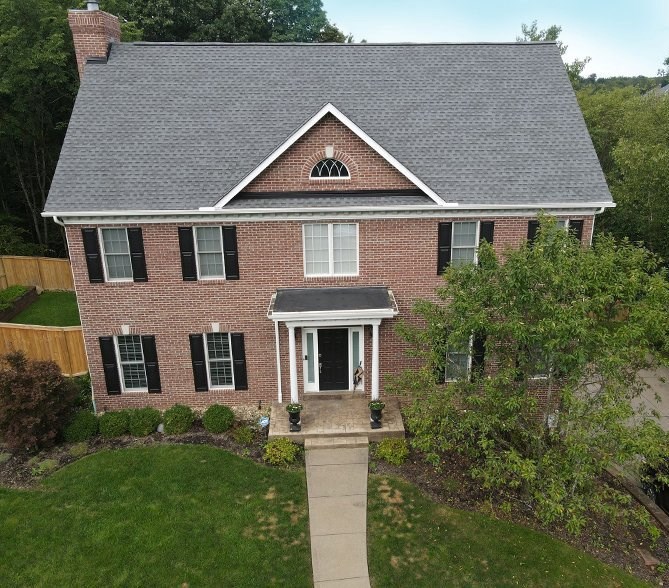 roofing contractor replacing asphalt shingles on two-story roof